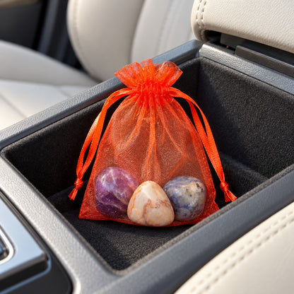 Bolsa laranja com três pedras roladas arrumada num compartimento da consola de um carro.